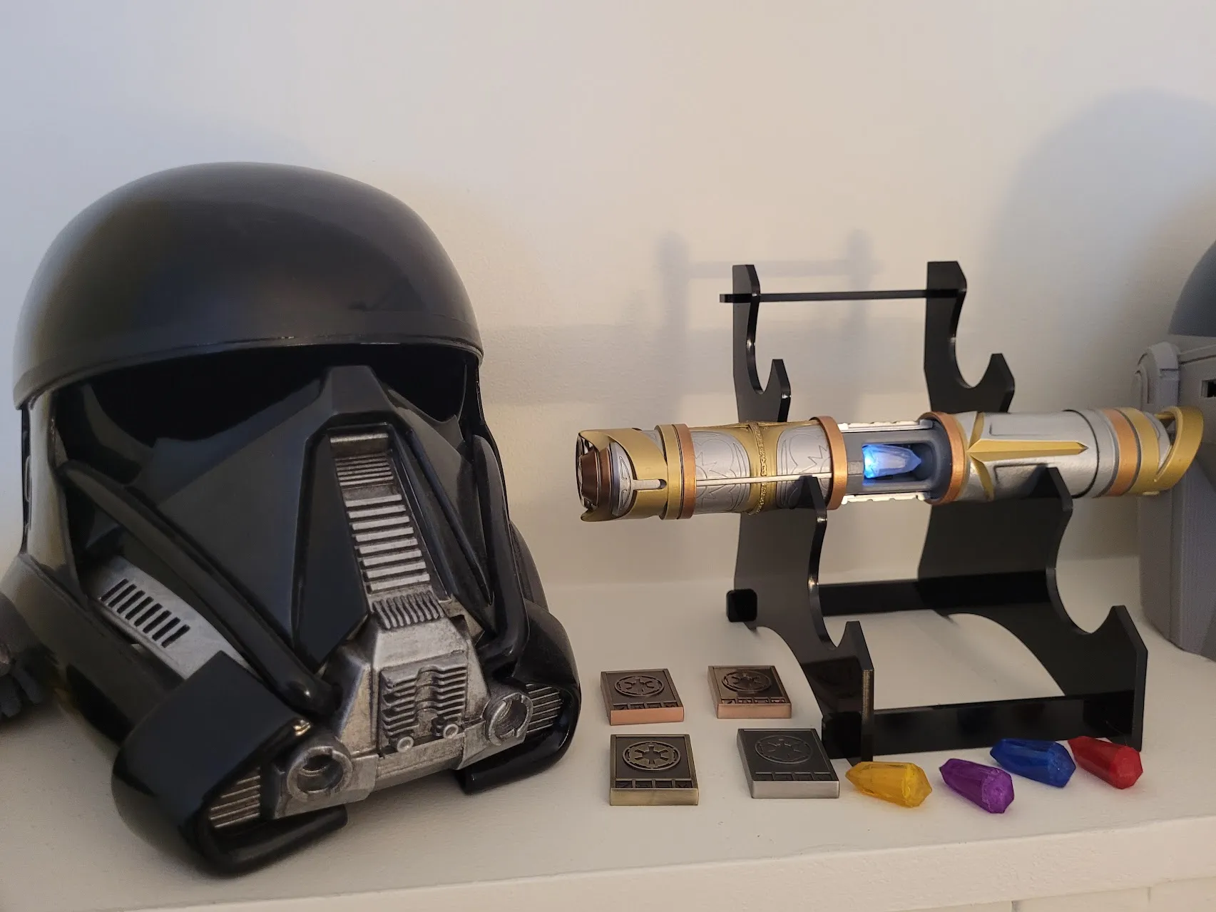 Death Trooper helmet on display beside a lightsaber and props